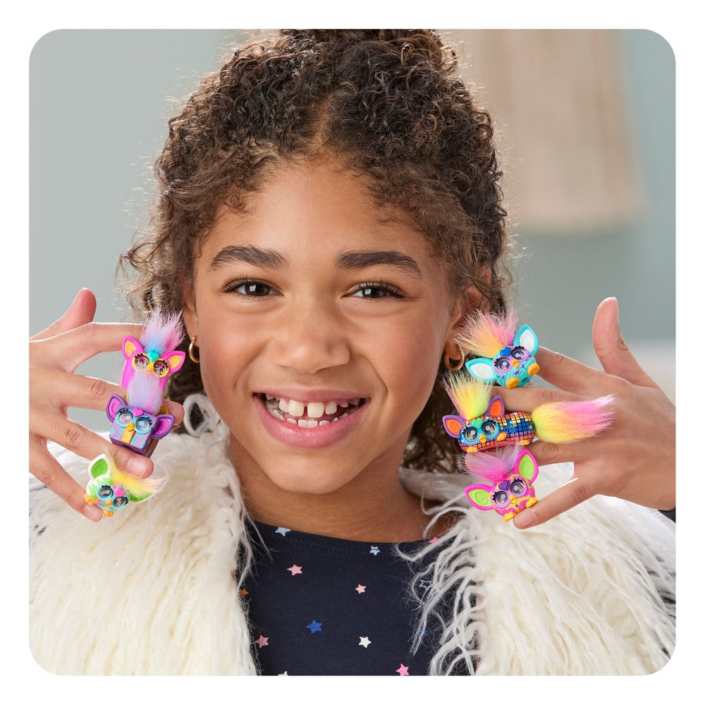 A kid smiling with mini Furby friends